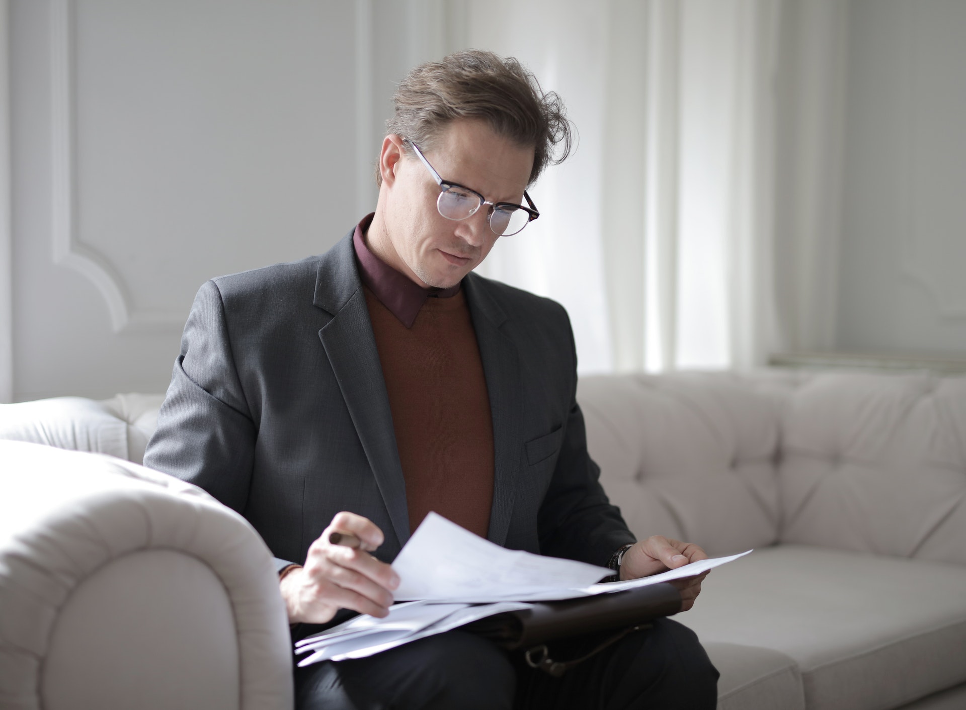 Man sitting on couch looking at paperwork living trust